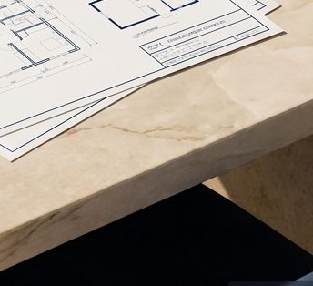 Sunlit marble worktop with technical drawings resting on it